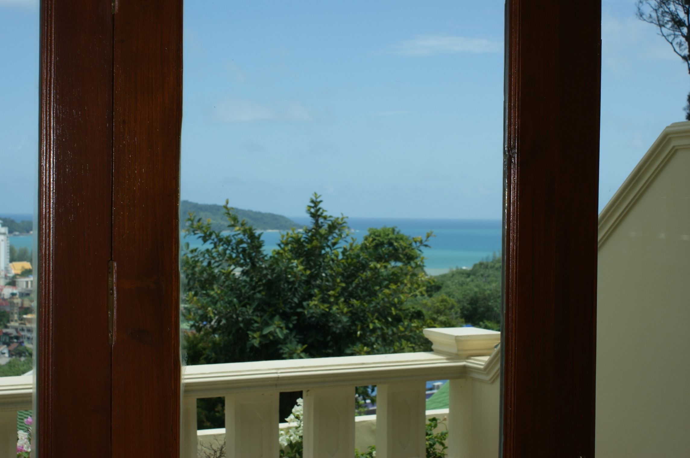 A balcony with a view of the sea and greenery.