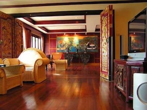 A traditional room with wooden flooring, a sofa, a chair, and a television.
