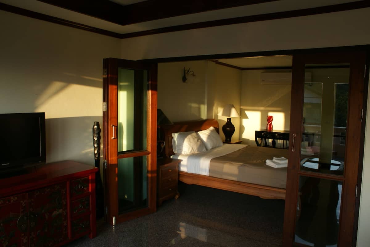A hotel room with a bed, a TV, a wooden cabinet, and a mirror.