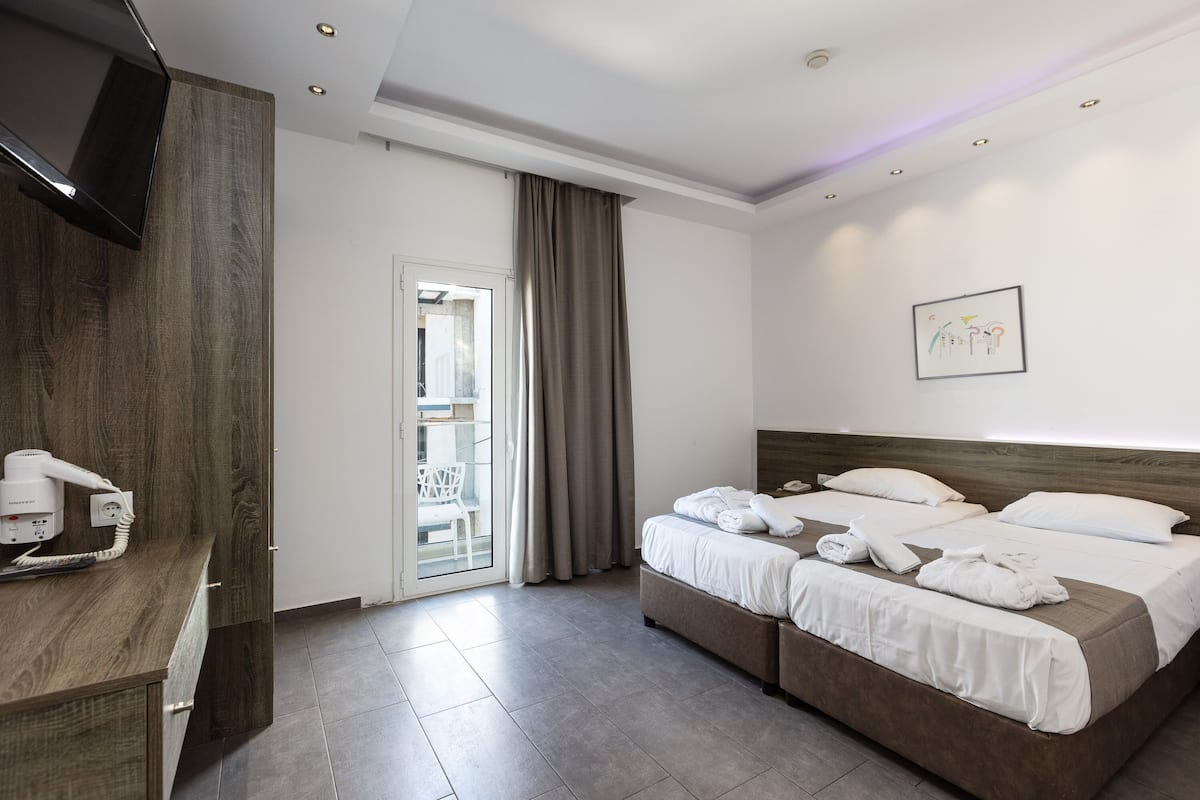 A hotel room with a bed, a desk with a hairdryer, a chair, and a window with curtains.