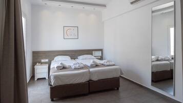 A modern hotel room with a large bed, bedside tables, a mirror, and a ceiling light.