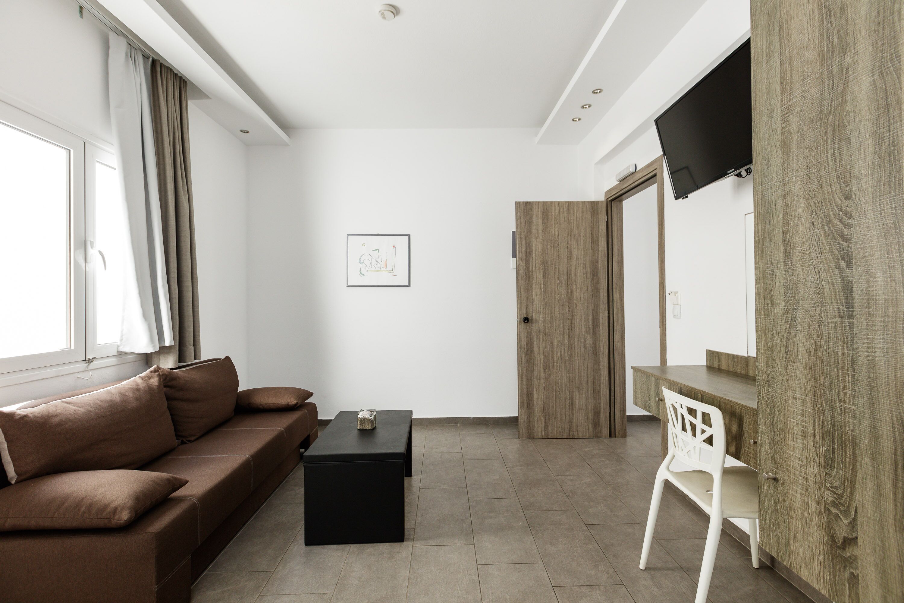 A modern living room with a sofa, coffee table, and a TV mounted on the wall.
