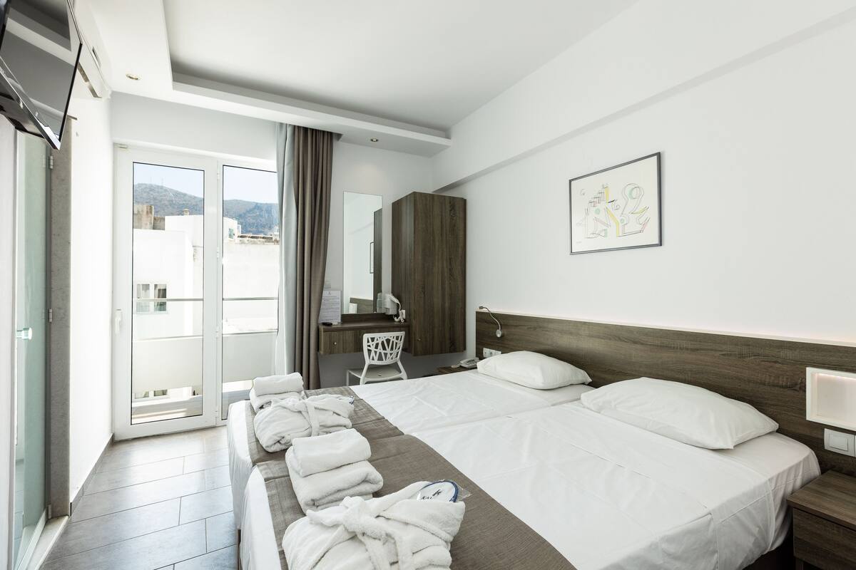 A hotel room with a bed, a desk, a chair, and a bathroom.