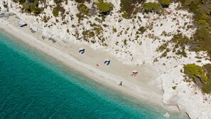Vista aérea de uma praia com águas turquesa cristalinas e areia branca.