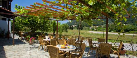 Eine Terrassengruppe im Freien mit Korbmöbeln und einer mit Wein bewachsenen Pergola.
