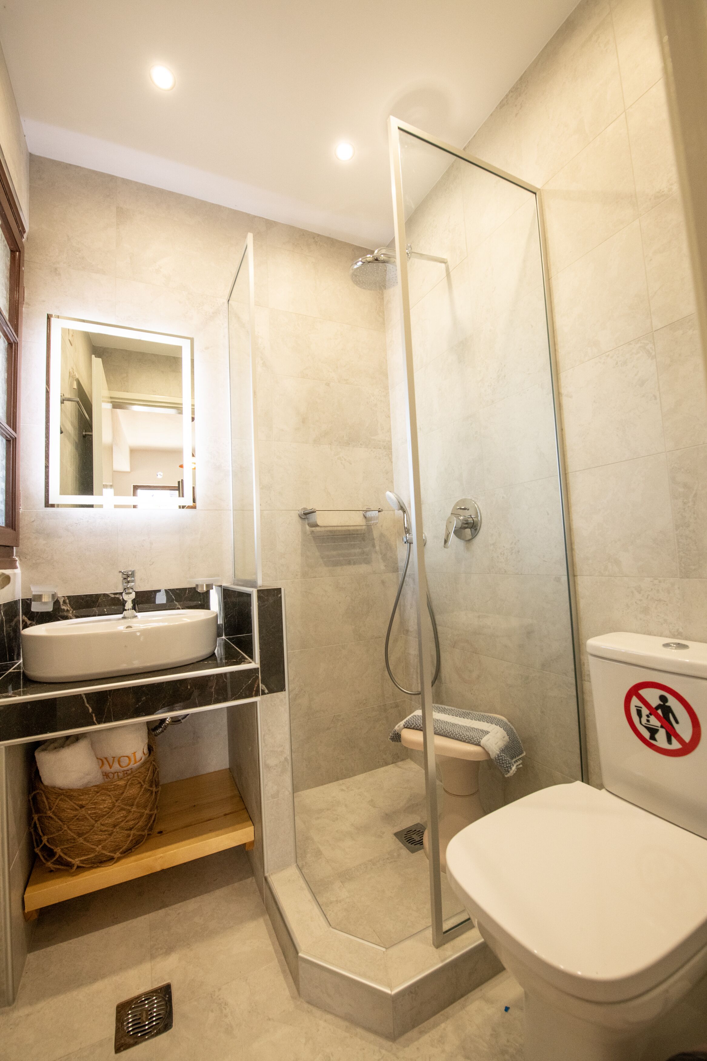 Un baño moderno con ducha de vidrio, un lavabo blanco y un inodoro.
