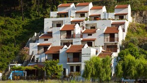A hillside building with multiple balconies and a sign reading "HOYOLA APARTMENTS". - Hovolo Hotel Apartments (Skopelos)