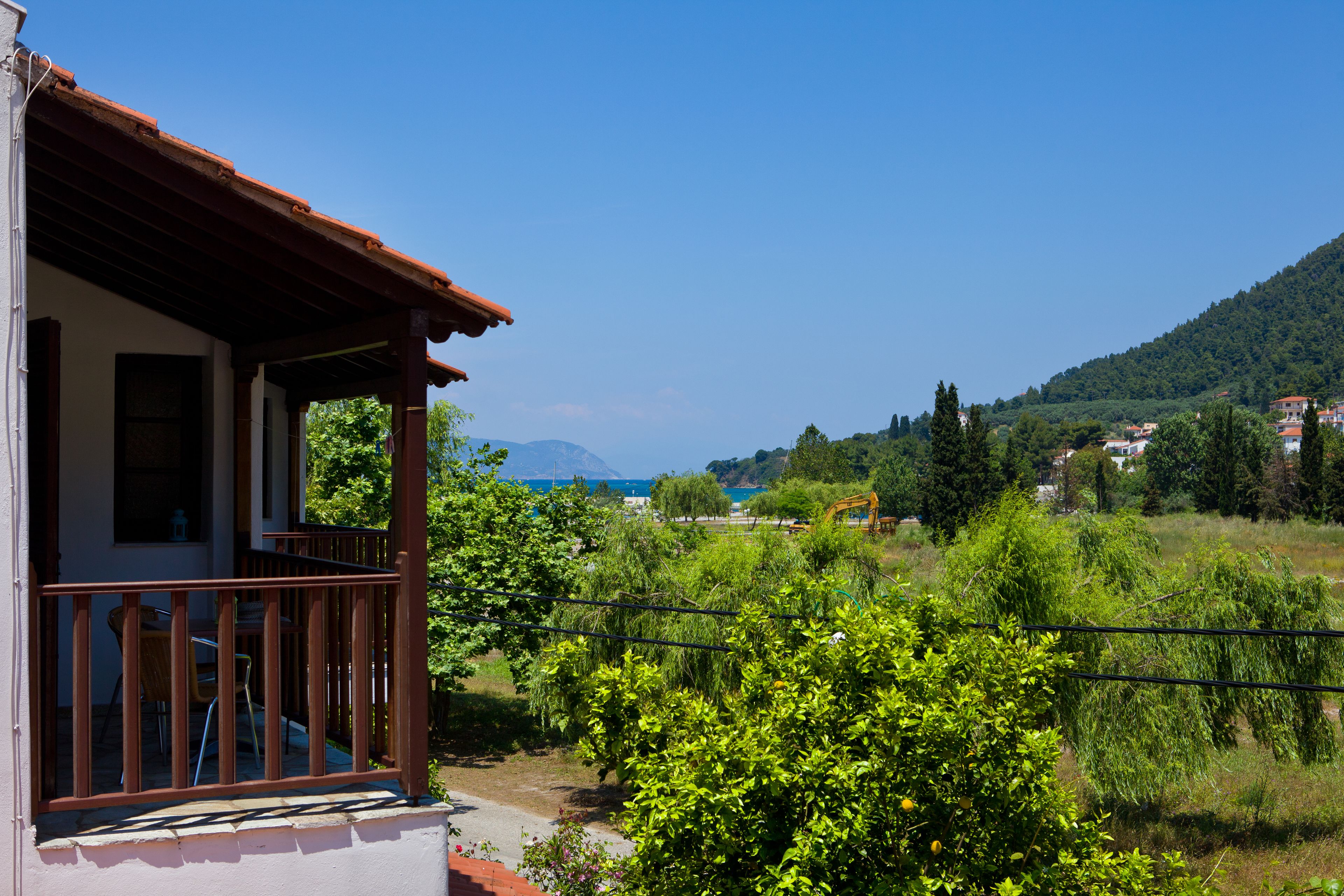 A house with a balcony overlooking a lush green landscape and a distant view of the sea and mountains.
