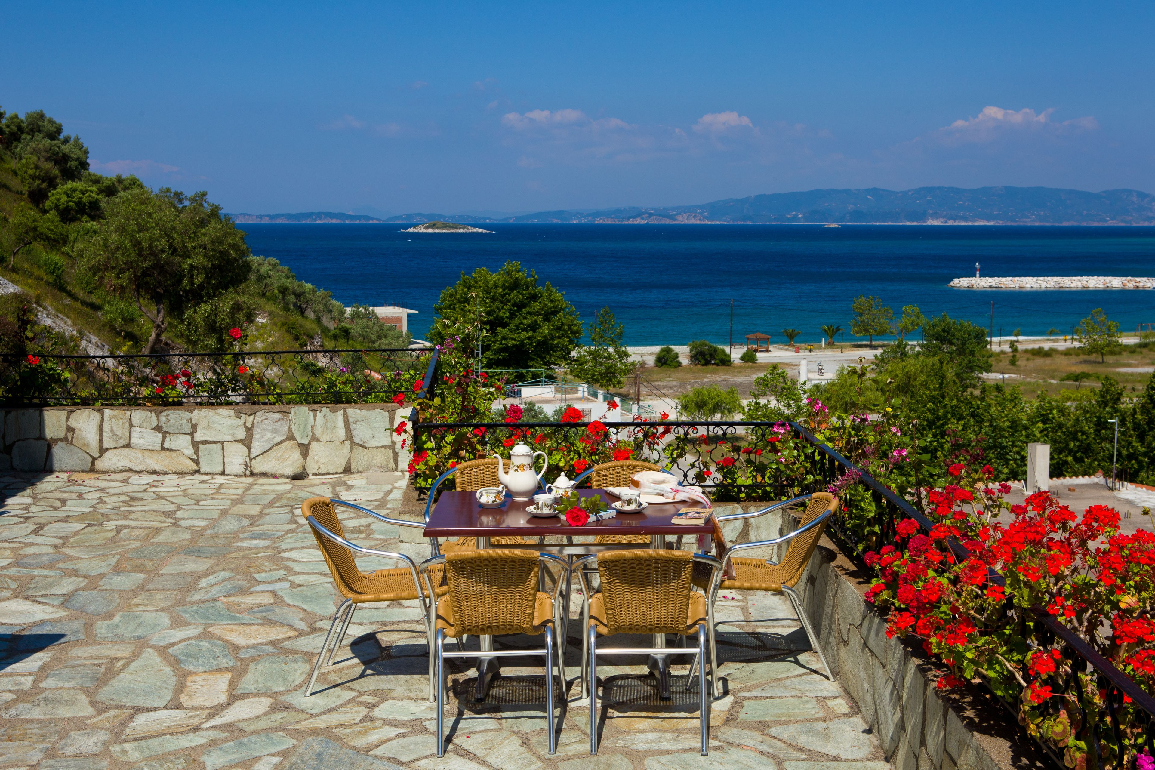 Un patio con una mesa lista para dos personas, con vistas al mar.