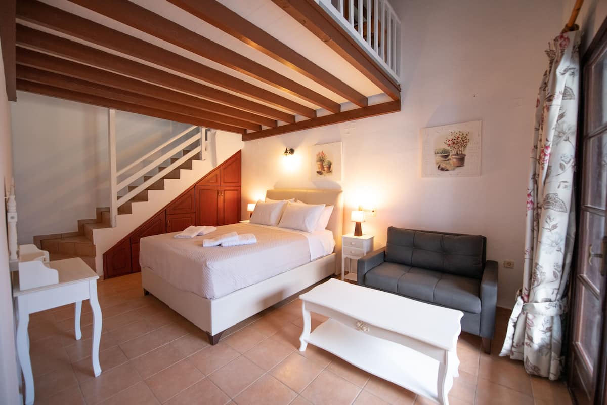 Une chambre à coucher comprenant un lit, une table de chevet, une commode et un canapé. Un escalier mène à un niveau supérieur.