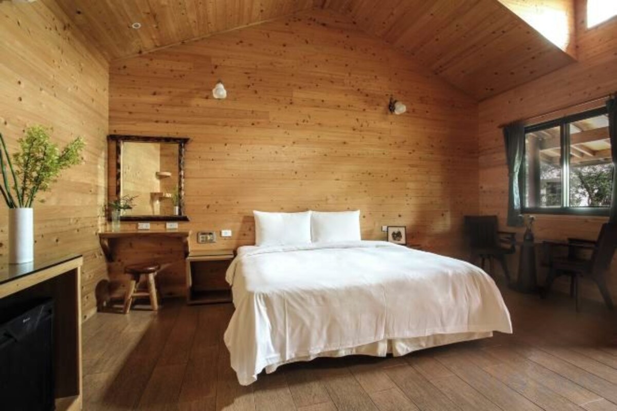 Een slaapkamer in een houten chalet, met een bed, een bureau en een stoel.