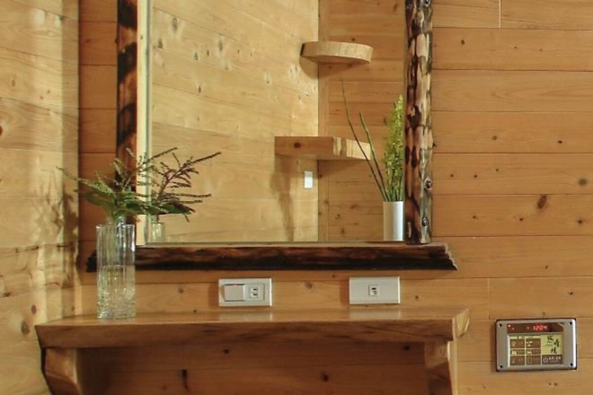 Un comptoir d’accueil en bois, agrémenté d’un miroir, d’une petite plante et d’une horloge numérique.