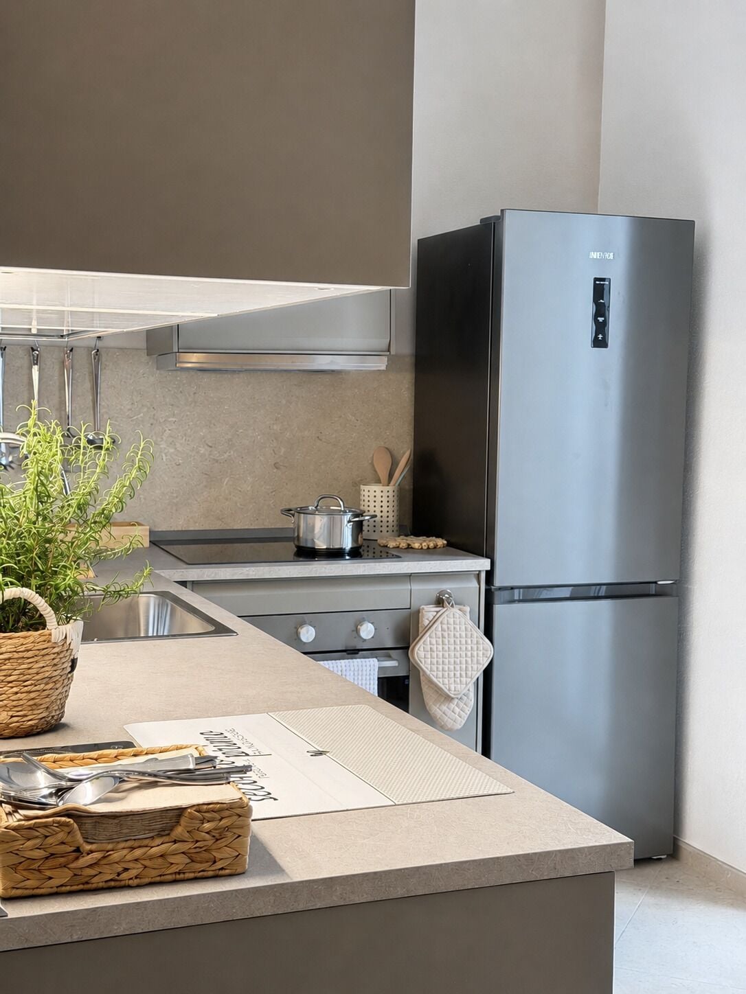 A modern kitchen with a stainless steel refrigerator, a built-in oven, and a granite countertop.