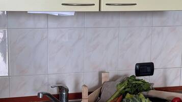 Une cuisine dotée d’un évier en acier inoxydable, d’un plan de travail en bois et d’une boîte étiquetée « GAFFECO » contenant des légumes.