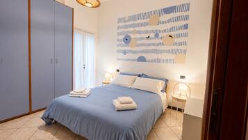 Una camera da letto con un letto, lampade sui comodini, un armadio e un quadro appeso al muro.