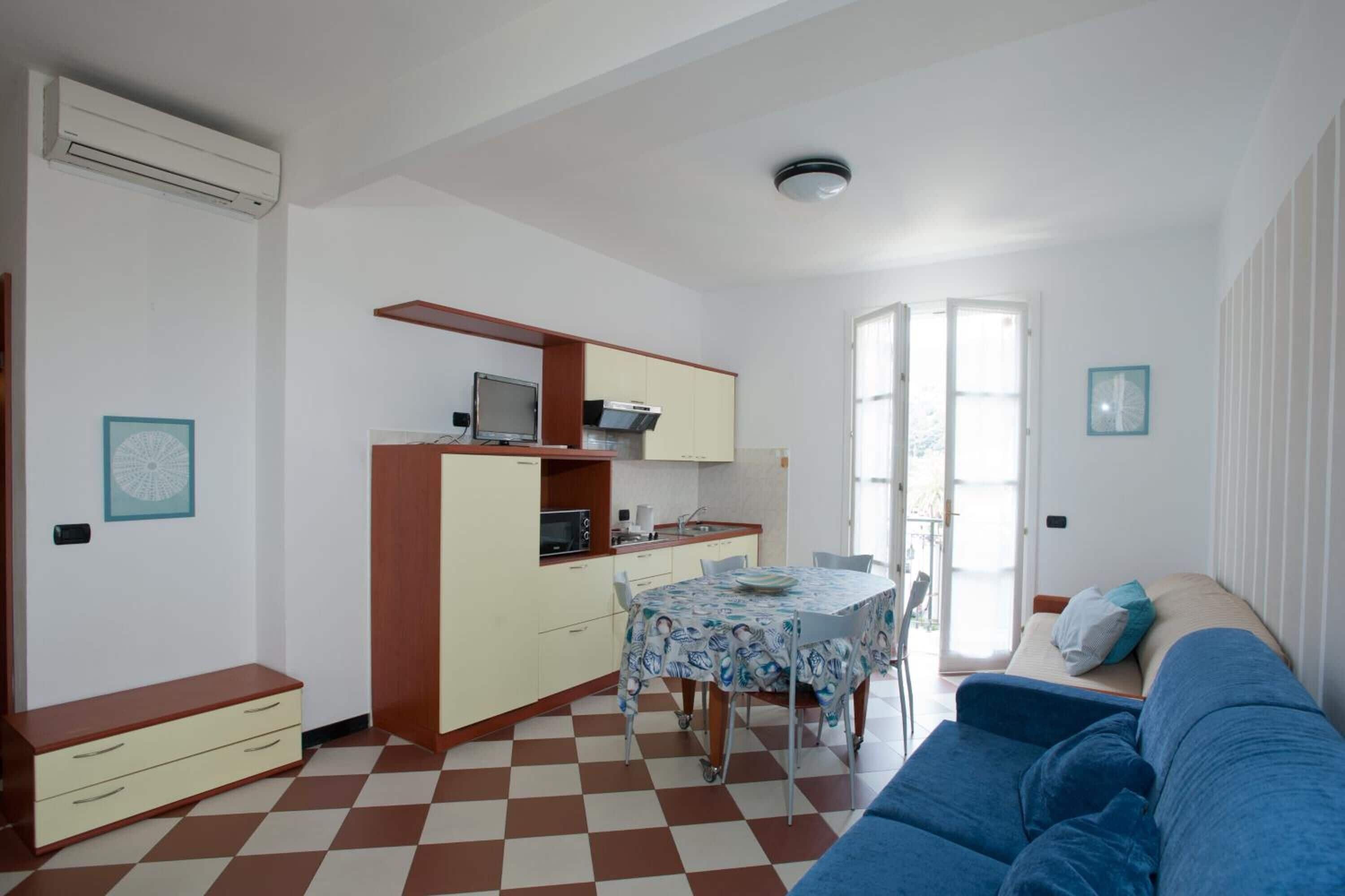 Un espacio habitable compacto con kitchenette, comedor y sofá.