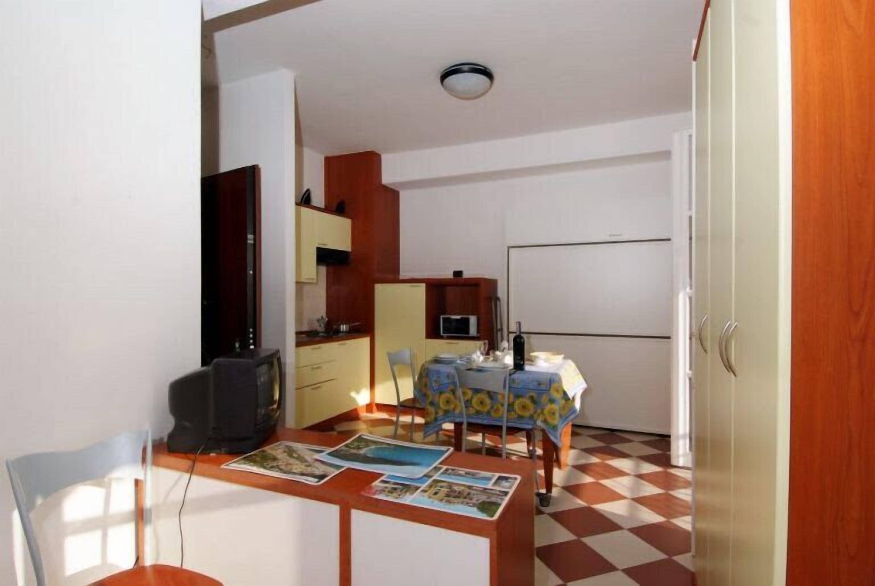 A compact kitchen with a dining area, a television, and a refrigerator.
