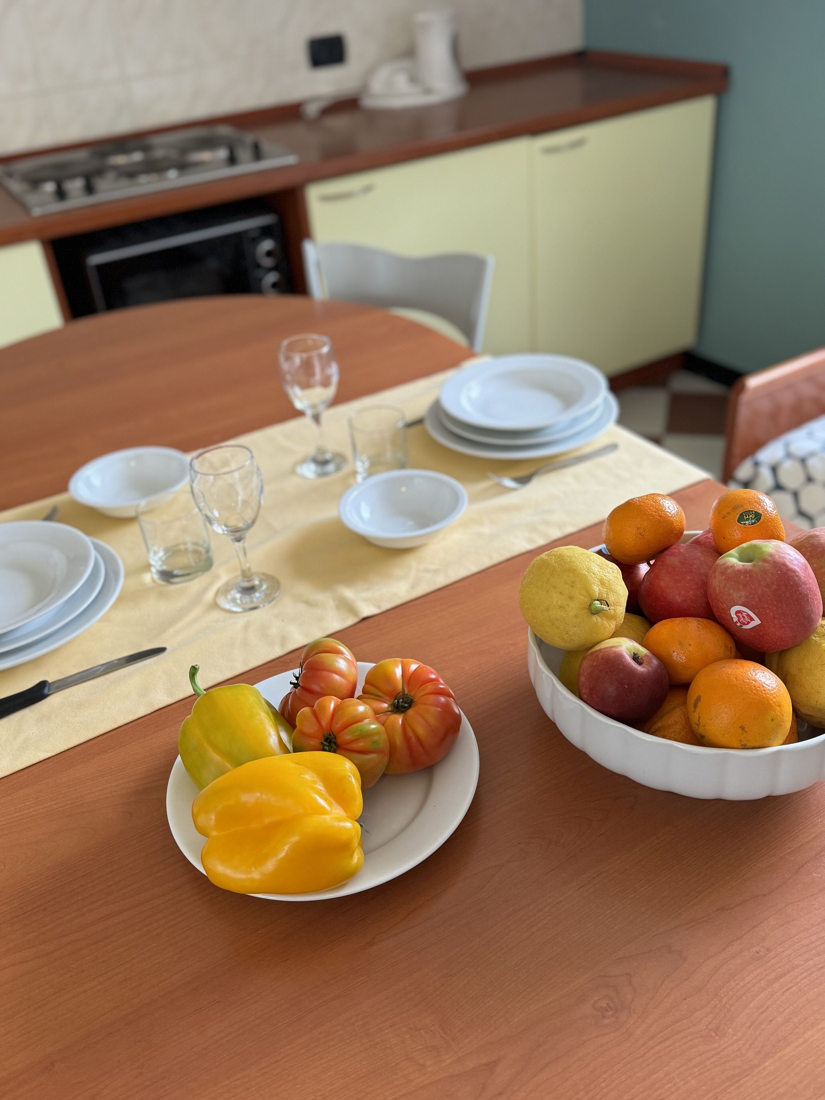 Een eettafel gedekt met borden, kommen en een schaal fruit.