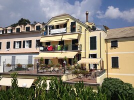 A multi-story building with balconies, outdoor seating, and potted plants.