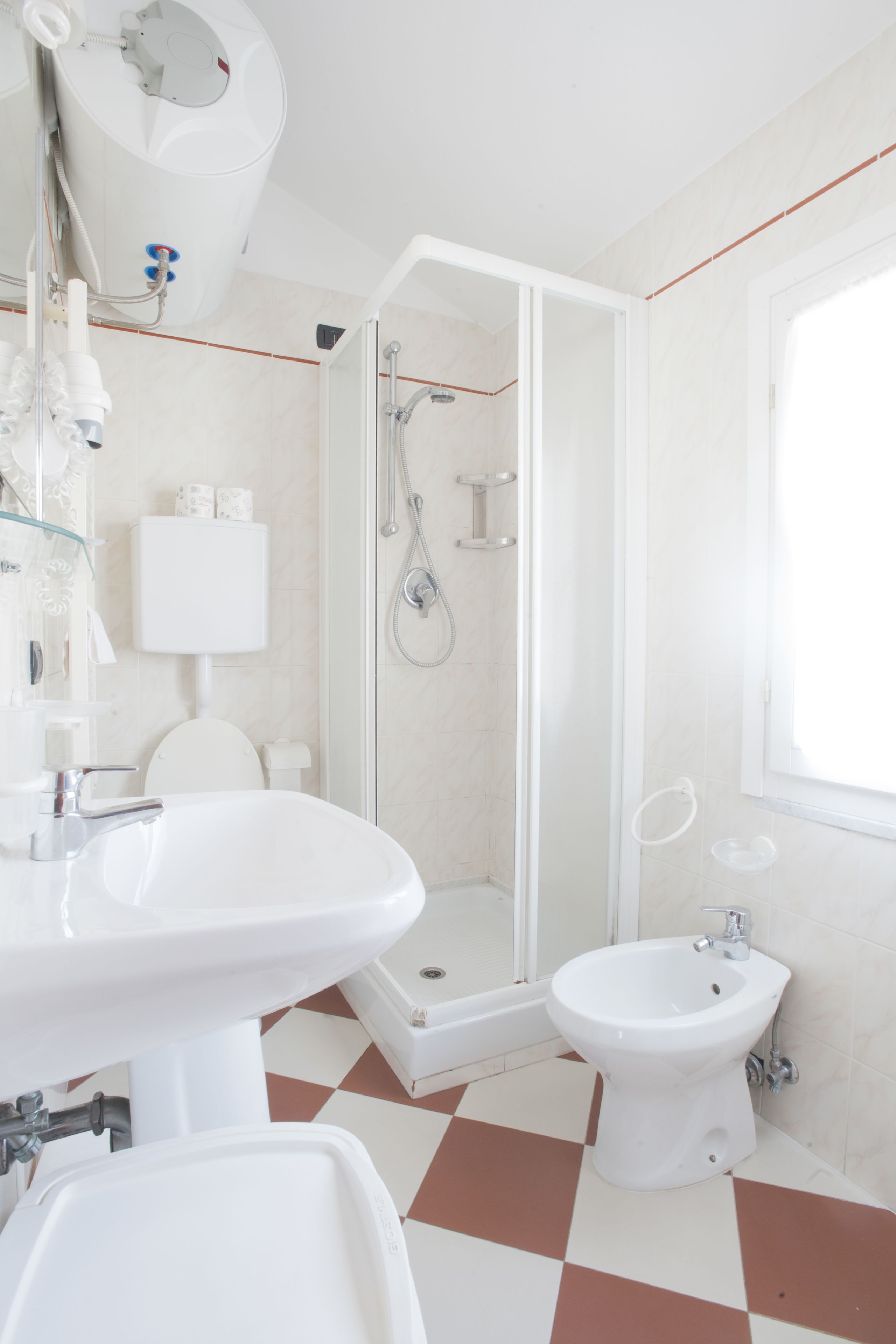 A modern bathroom with a shower, bidet, and two sinks.
