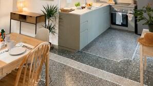A modern kitchen with a central island, a dining area with a table and chairs, and a loft bedroom with a balcony. - Giada Residence (Moneglia)