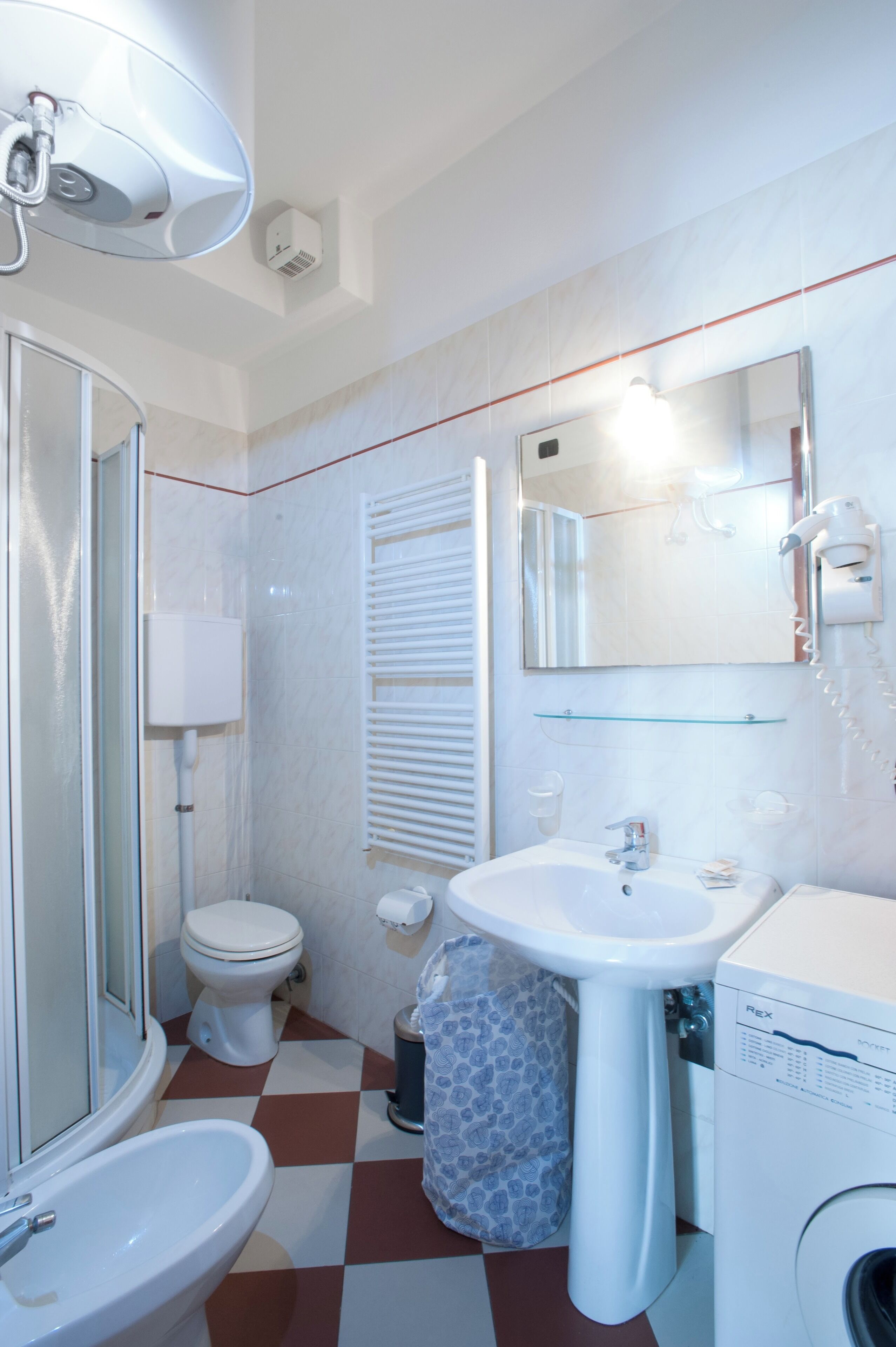 A bathroom with a toilet, sink, mirror, and shower.