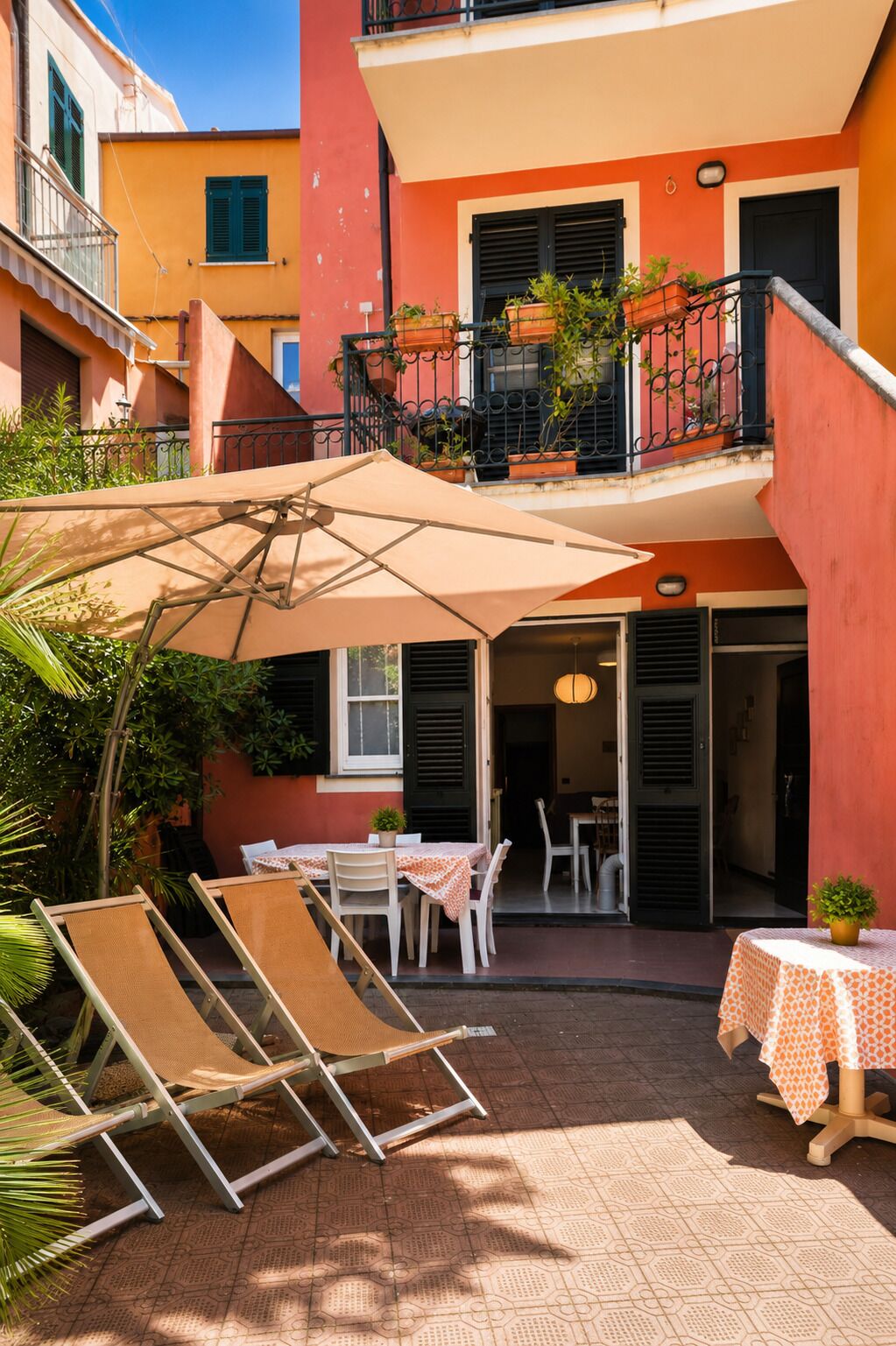 Un patio con mobiliario exterior, una mesa con mantel estampado y plantas en macetas.