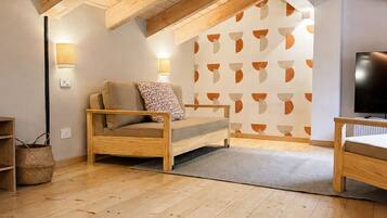 Ein gemütliches Schlafzimmer im Loft-Stil mit freiliegenden Holzbalken, einem Bett, einem Fernseher und einer Wand mit Muster.
