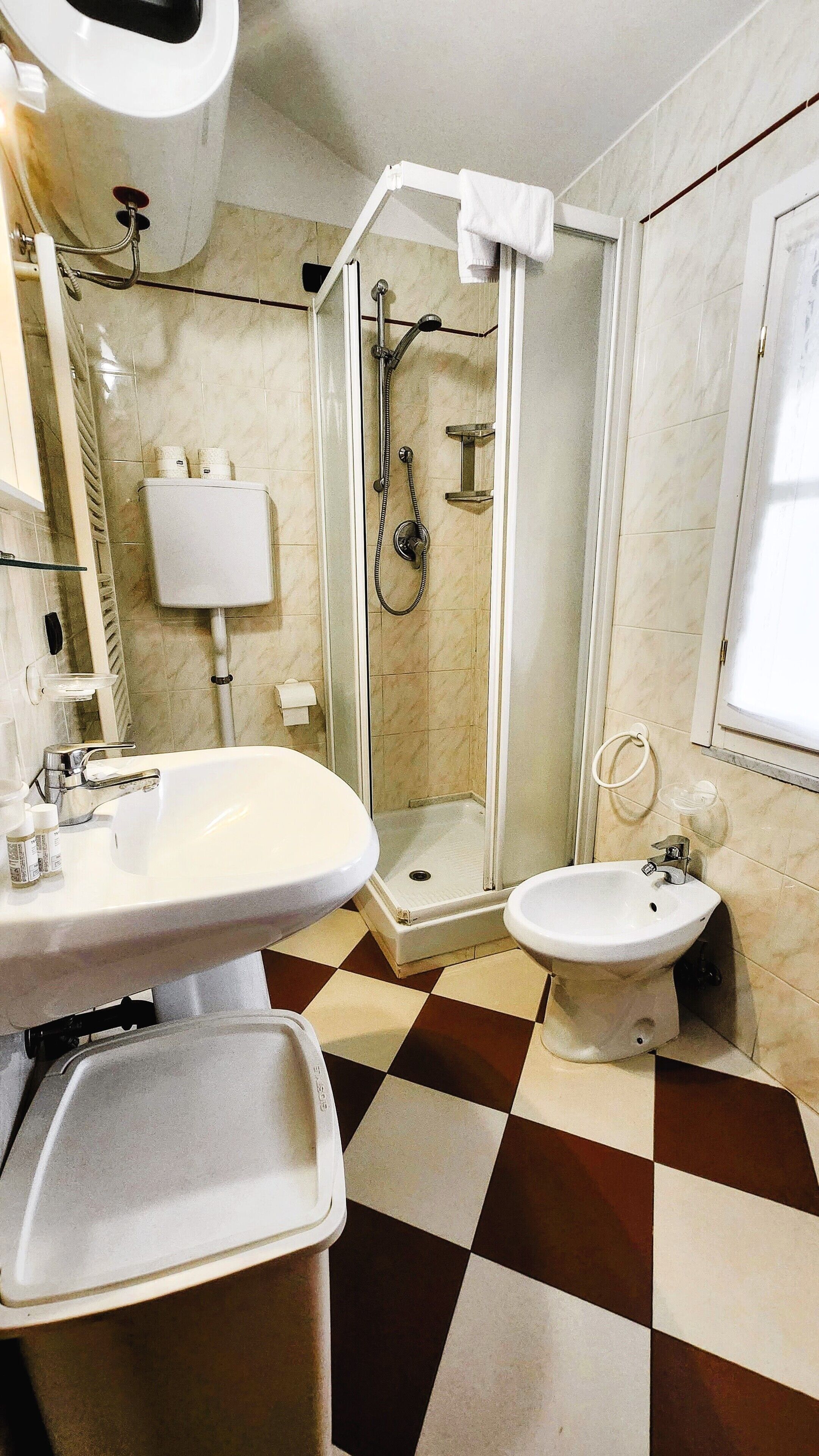 A bathroom with a shower, two sinks, a bidet, and a toilet.