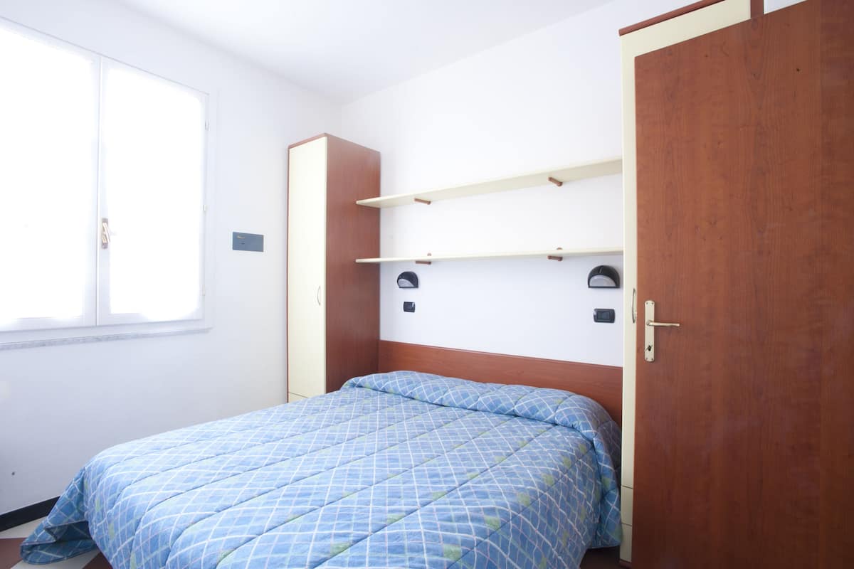 A bedroom with a bed, a wardrobe, and a window.
