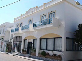 Un hotel de dos pisos con fachada blanca, balcones azules y ventanas arqueadas.