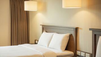 A hotel room with a neatly made bed, a headboard with a textured design, and two wall-mounted lamps.