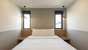 Een moderne hotelkamer met een groot bed, twee nachtkastjes en een hoofdbord met ingebouwde verlichting.