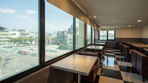 Moderni ravintola, jossa on suuret ikkunat, joista avautuu näkymä kaupunkiin.