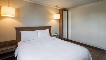 A hotel room with a large bed, two bedside lamps, a nightstand, and a mirror.