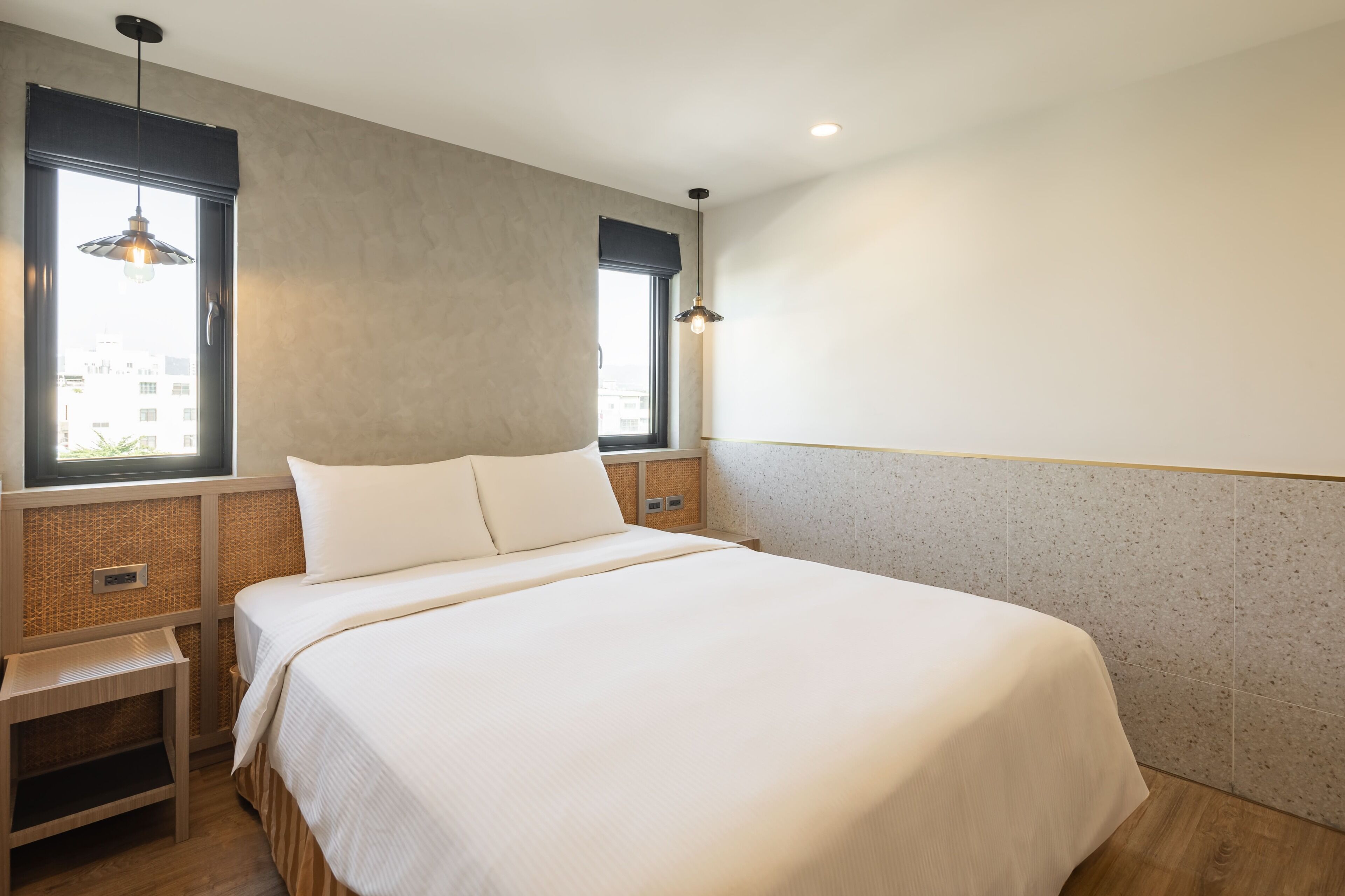 Habitación de hotel con una cama grande, dos mesitas de noche, un ventanal con vistas y una lámpara fijada a la pared.