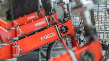 Una fila de bicicletas rojas con la etiqueta 'FD806' en un aparcamiento.