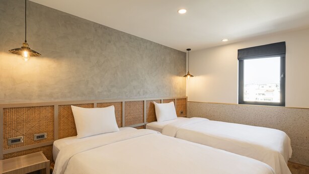 Habitación de hotel con dos camas, un ventanal grande y una pared con textura.