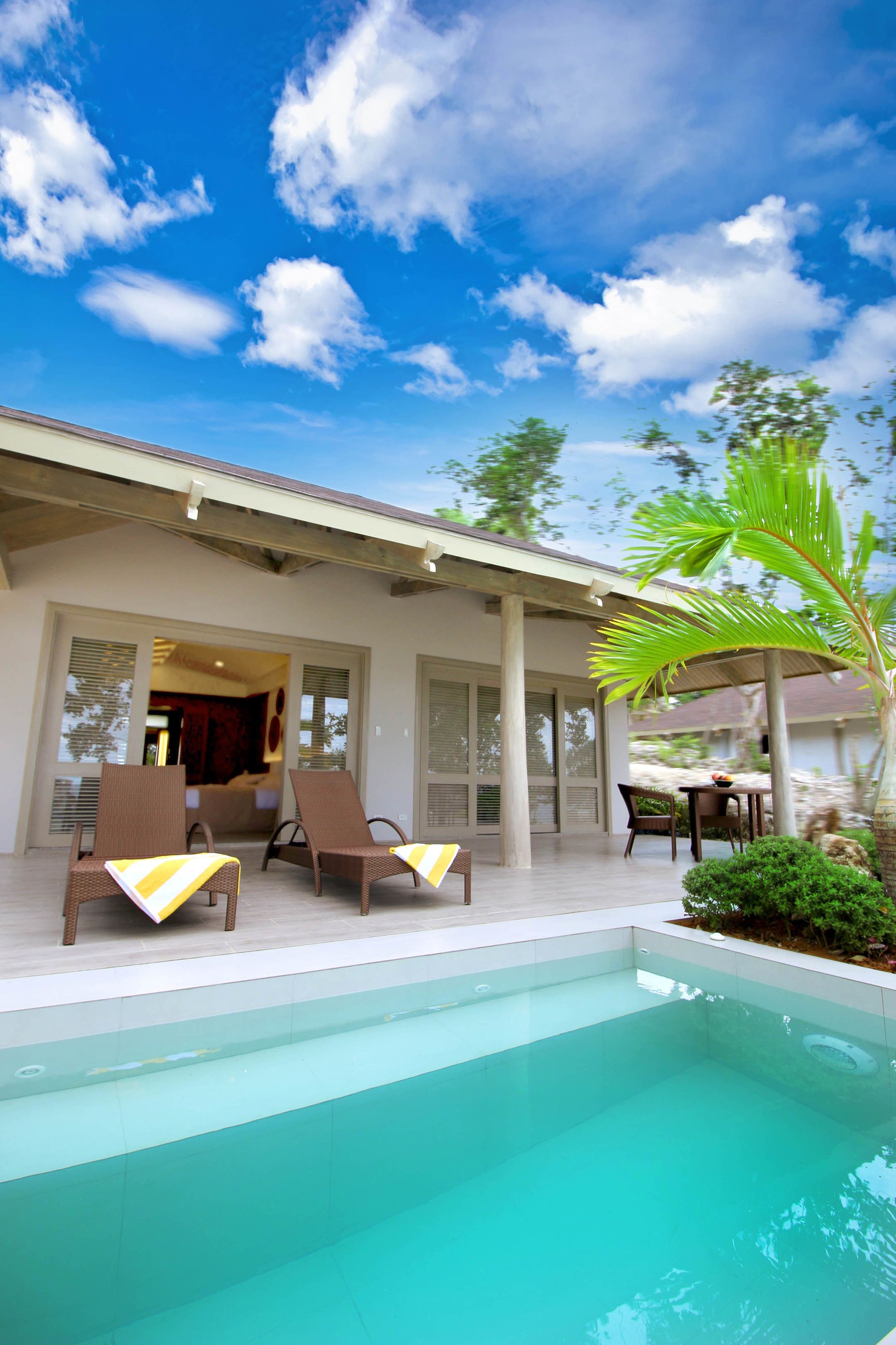 A poolside area with lounge chairs, a covered seating area, and a view of the sky.