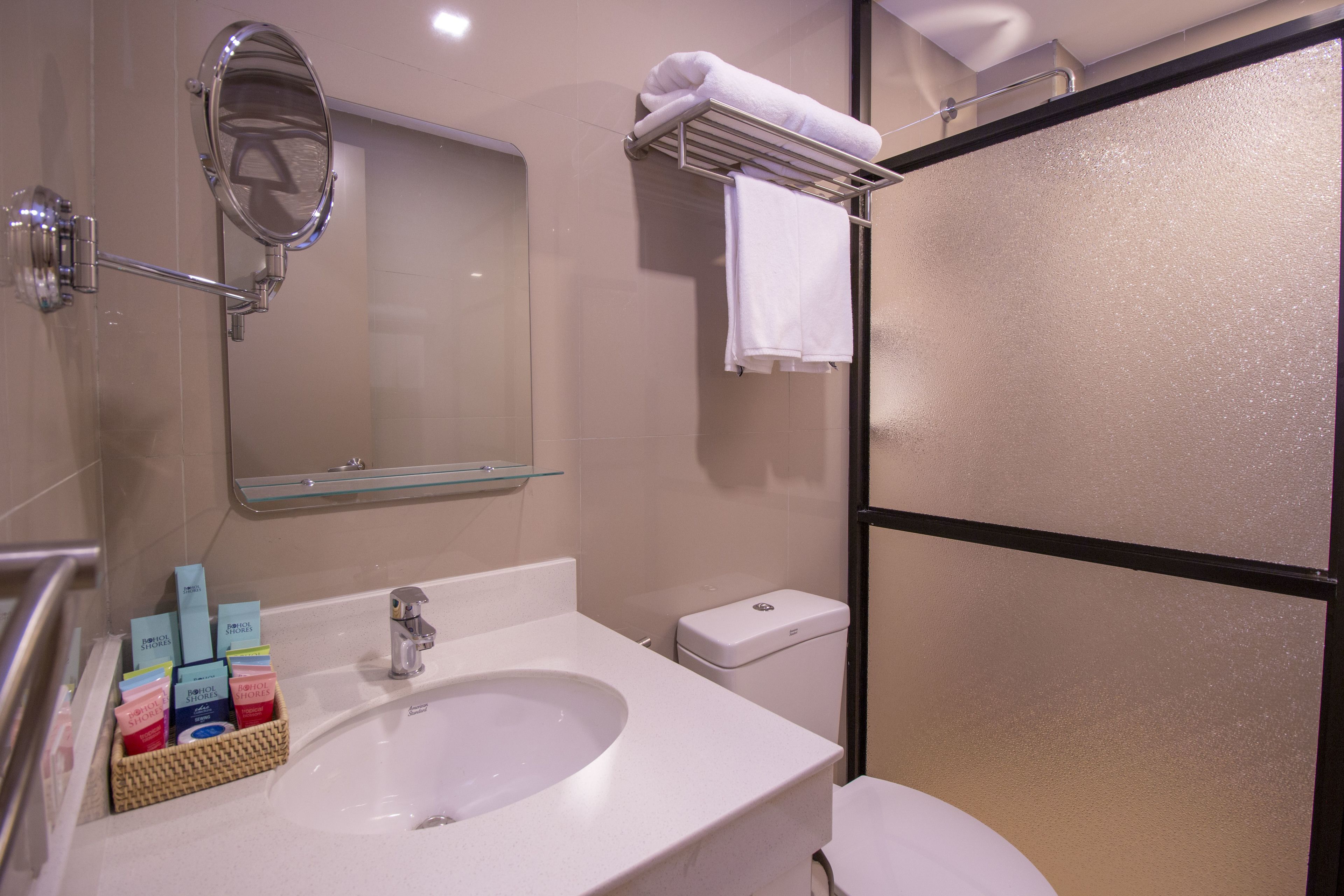 Baño con lavamanos, espejo e inodoro. Hay artículos de aseo en una cesta sobre el lavamanos.