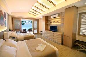 A modern hotel room with two beds, a TV, a desk, and a view of the sea. - Bohol Shores (Dauis)