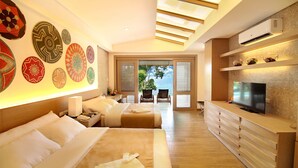 A modern hotel room with a large bed, a TV, a dining area, and a view of the sea through the windows. - Bohol Shores (Dauis)