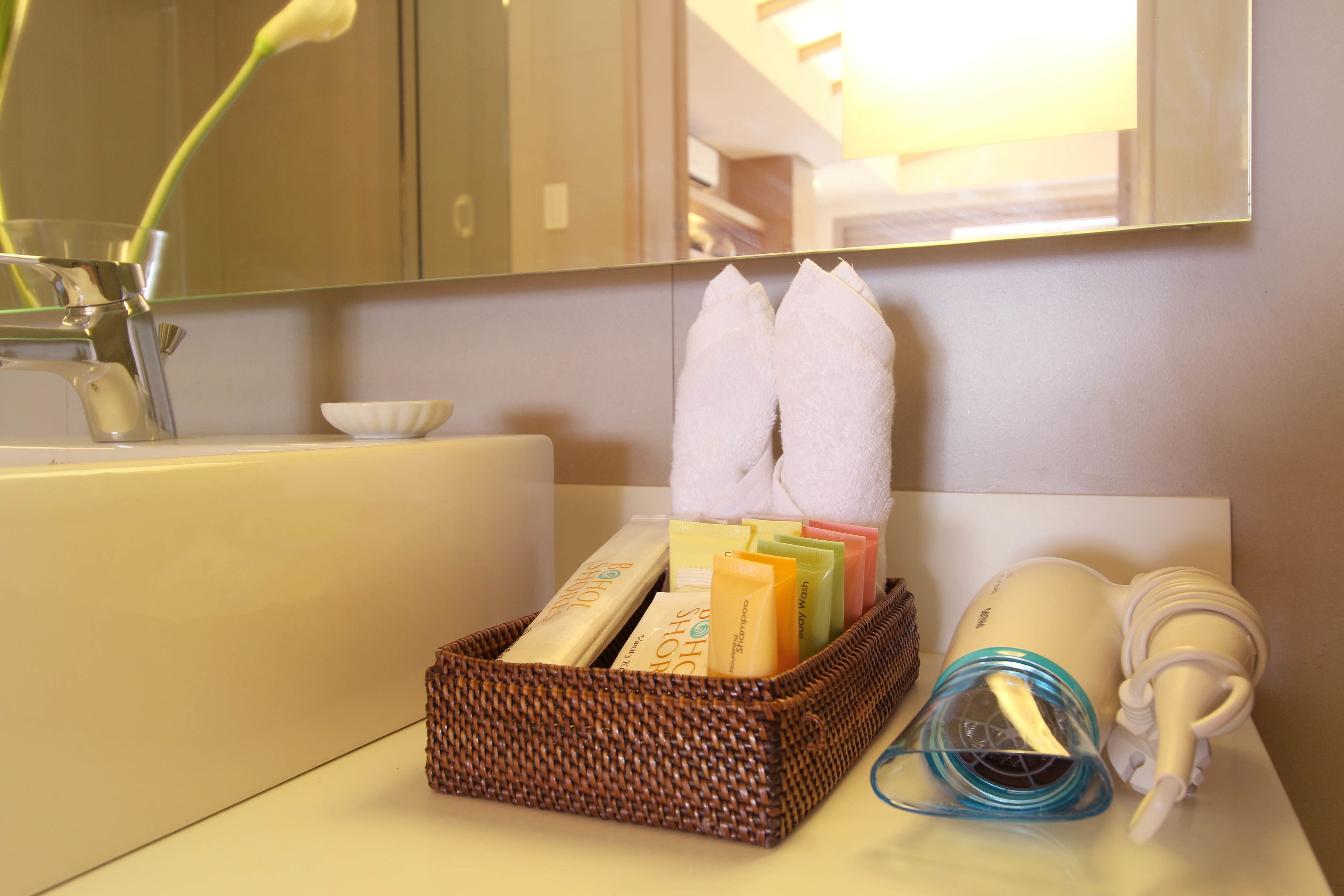 Ein Badezimmer mit Waschbecken, Spiegel, einem Tablett mit Pflegeprodukten und einem Fön.