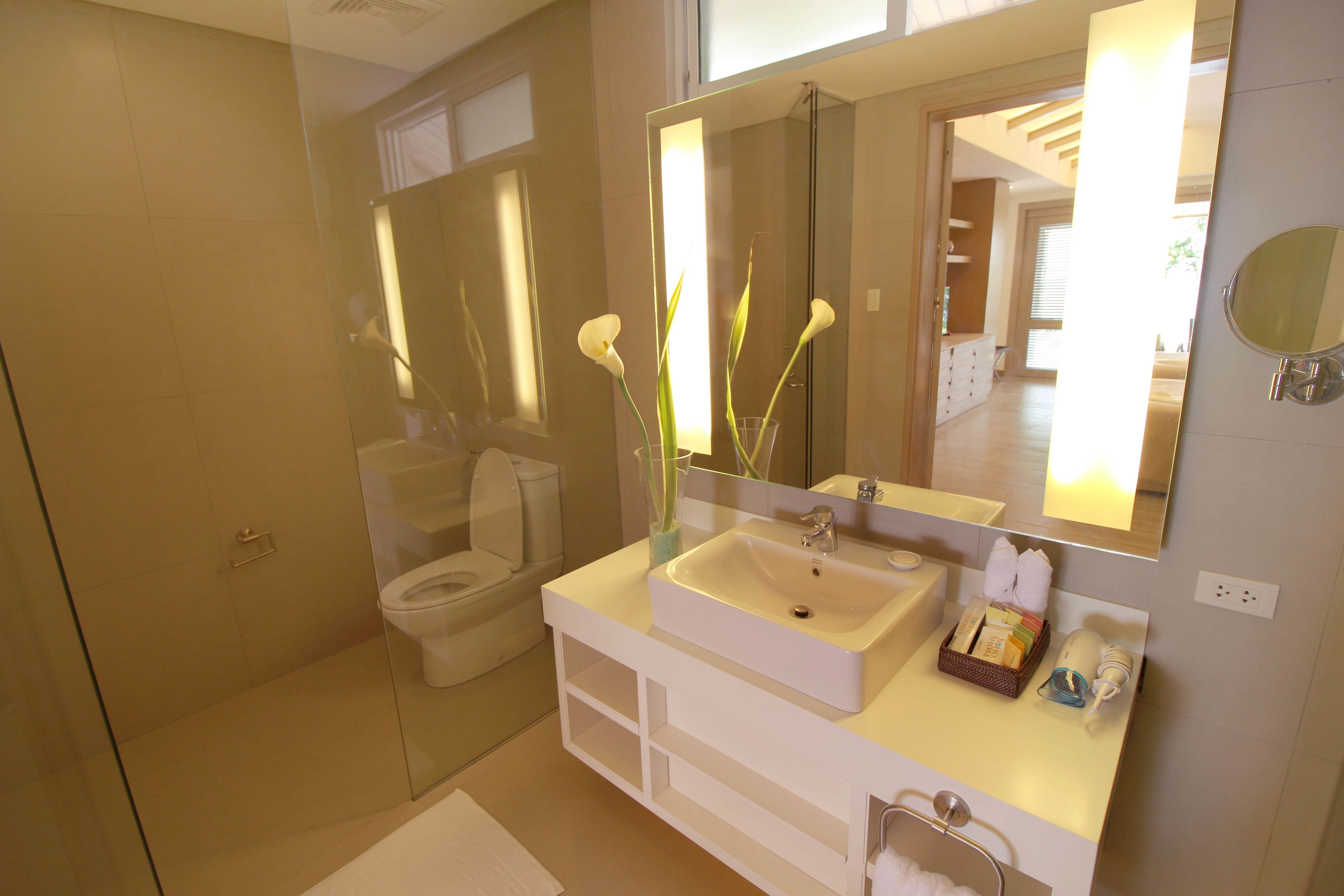 A modern bathroom with a large mirror, a white sink, and a glass-enclosed shower.