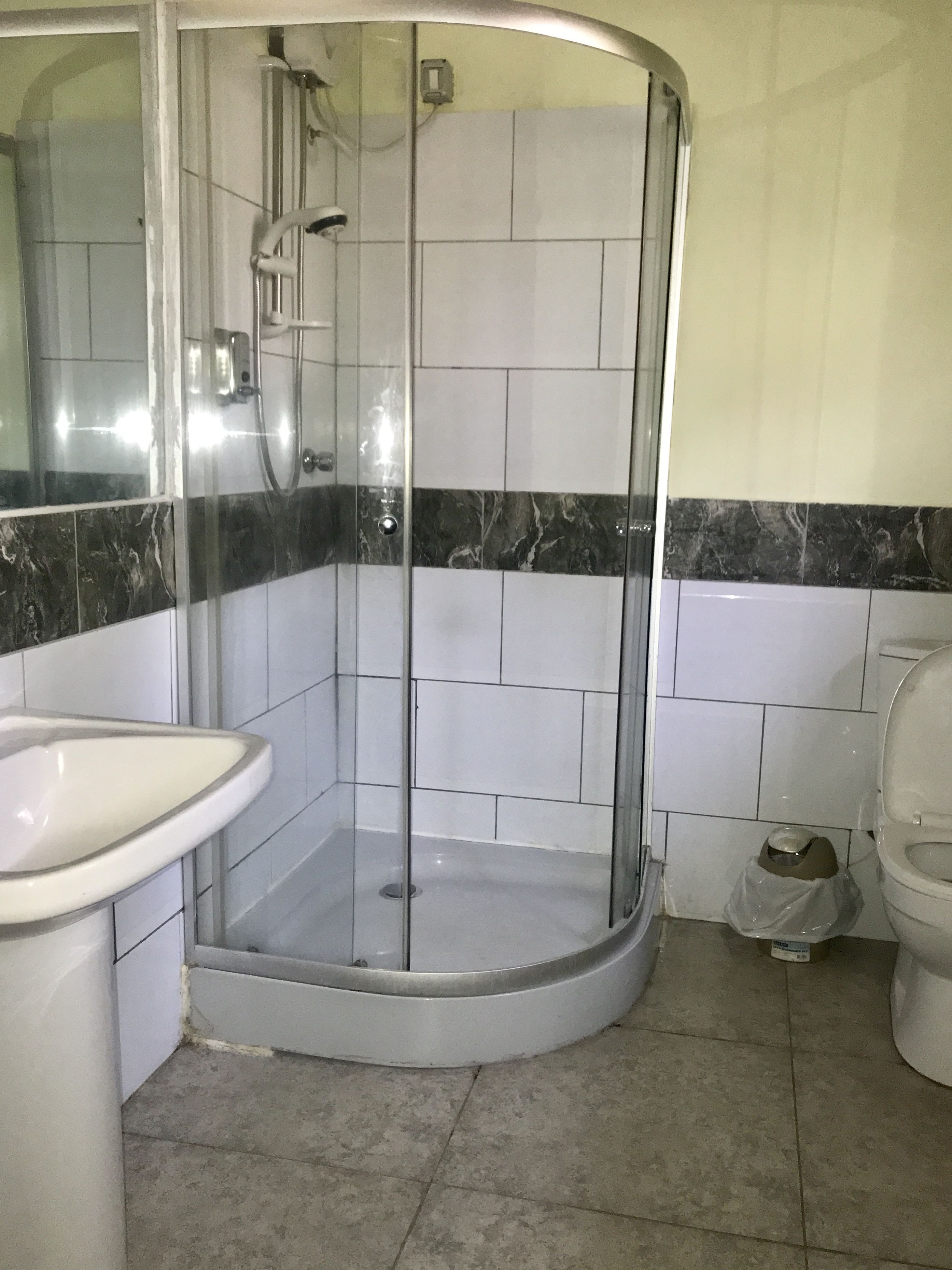 Une salle de bain avec une douche à parois de verre, un lavabo et des toilettes.