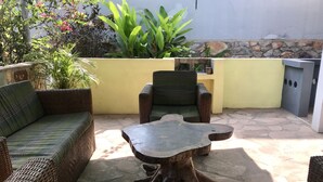 Eine Terrasse mit Korbmöbeln, einem Steintisch und einer Steinwand.
