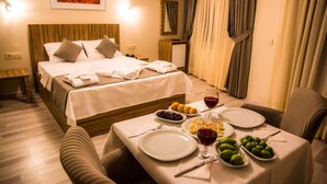 A hotel room with a bed, a dining table set with plates, glasses, and fruits, and a painting on the wall. - Berlin Otel Nişantaşı (Istanbul)