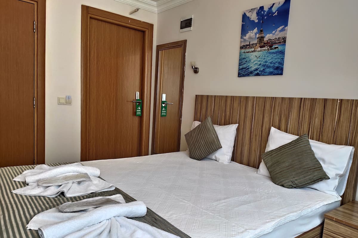 Una habitación de hotel con una cama grande, cabecero de madera y un cuadro de una escena costera.