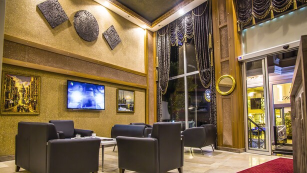 A lobby with a red carpet, black leather sofas, a TV, and a large window with curtains. - Berlin Otel Nişantaşı (Istanbul)