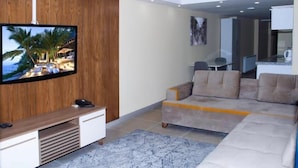 A modern living room with a flat-screen TV, a beige sofa, and a wooden accent wall. - Berlin Otel Nişantaşı (Istanbul)
